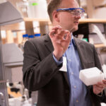 man with toothpick and protective glasses in lab