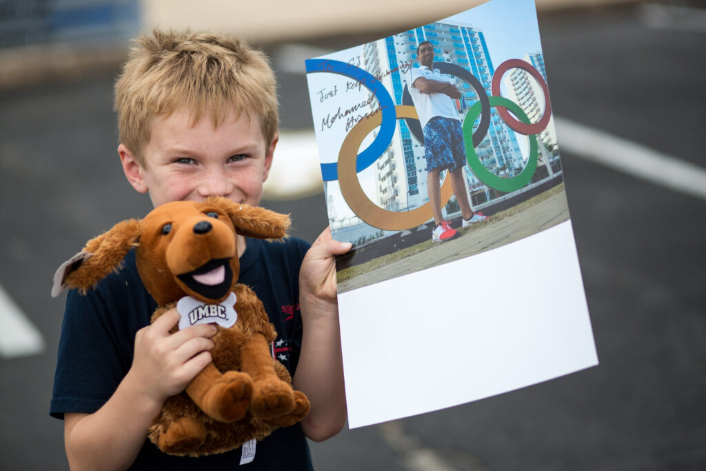 Young festival-goer holds a signed poster by UMBC Olympic swimmer Mohamed Hussein ‘14, mechanical engineering and current graduate student.