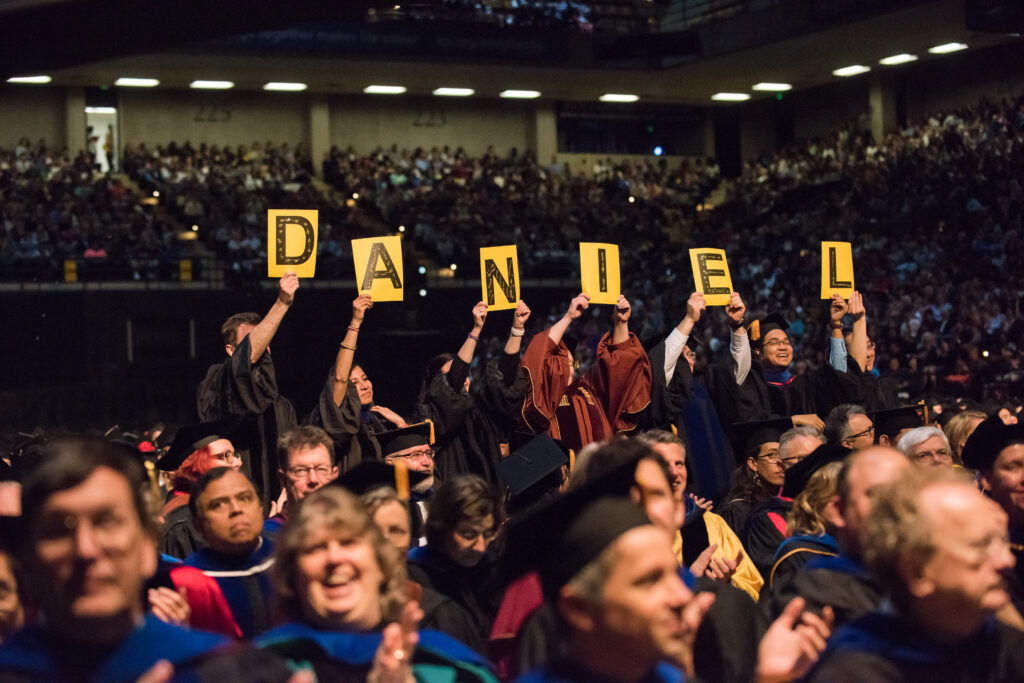 Professors hold signs spelling out D-A-N-I-E-L