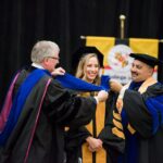 Student receives her PhD in hooding ceremony with faculty member and provost