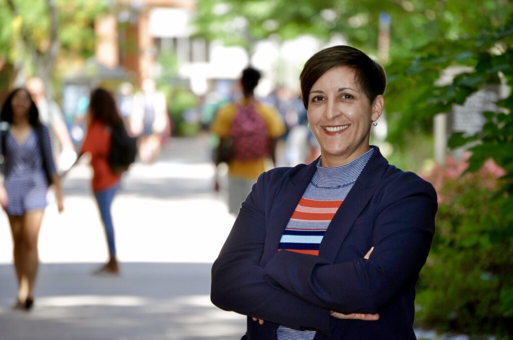 Outdoor portrait of smiling woman in striped shirt and blazer.