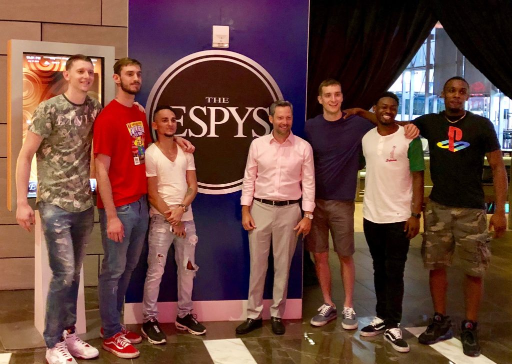 A diverse group of young men pose together for a photo in front of a sign that reads "The ESPYS"