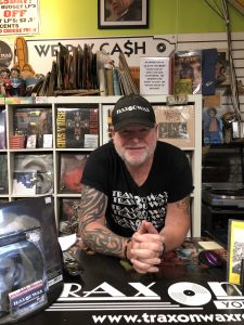 A man with a very tattooed arm standing at a desk.