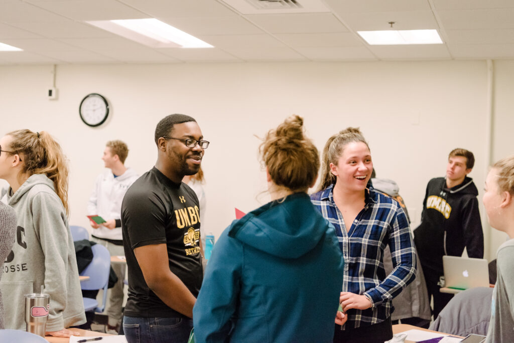 Small group of college students chats in a classroom.