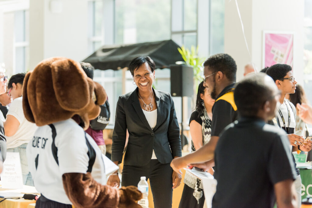 Yette Mozie-Ross with UMBC mascot True Grit and students in 2019