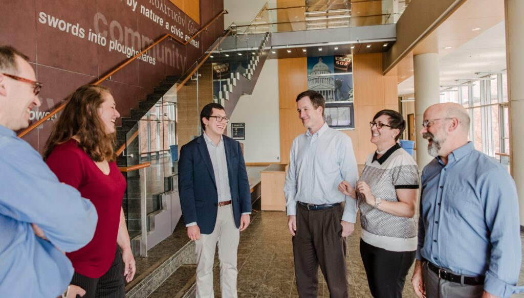 A group of faculty and staff standing in a circle by a stairwell.