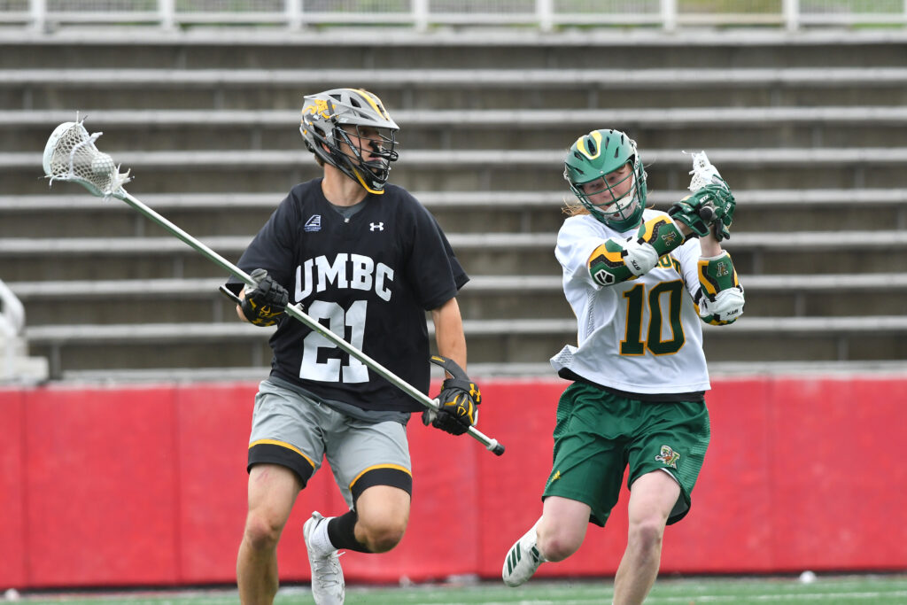 Two men's lacrosse players from different teams face off on the field