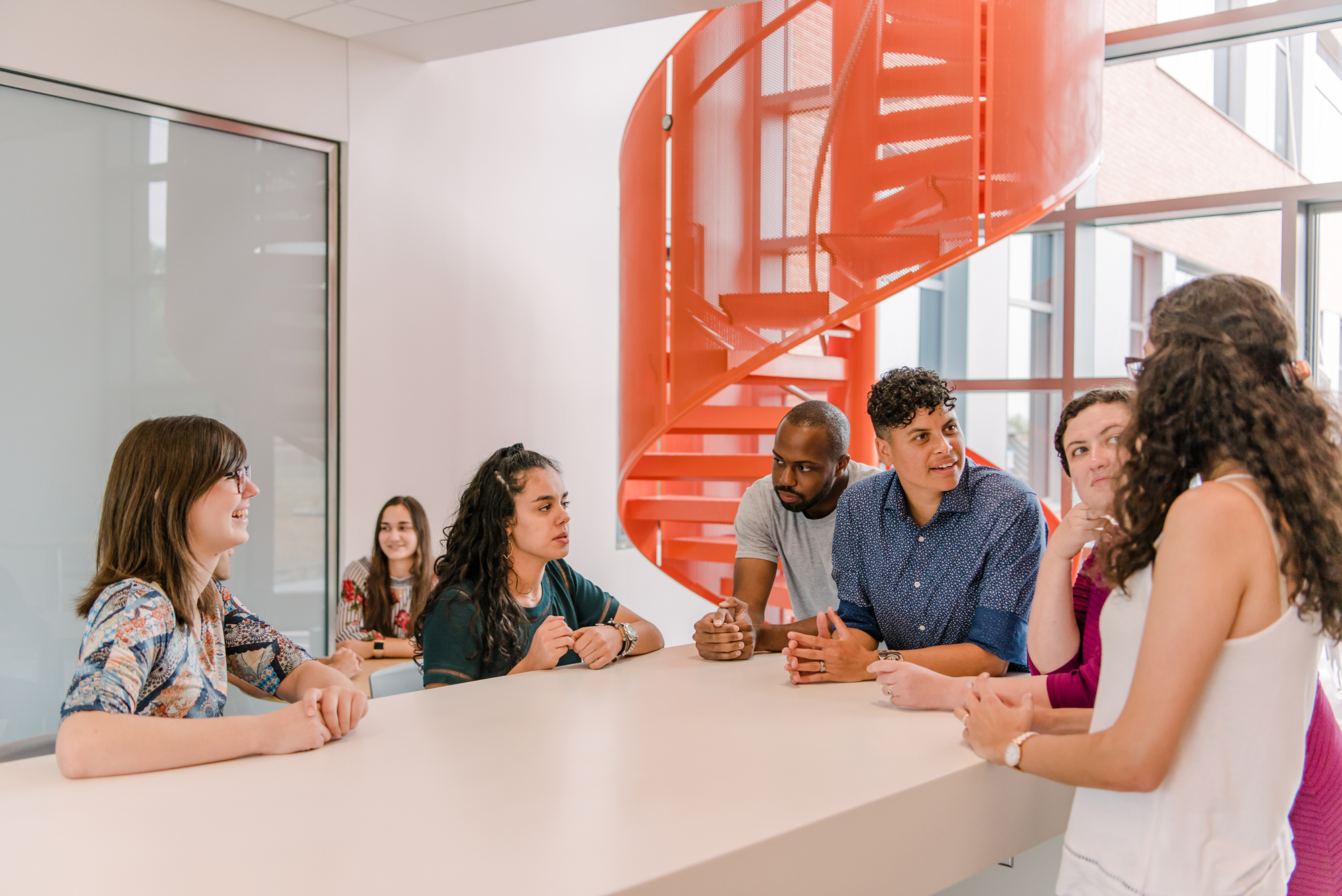 Group talk in front of red stairs in ILSB building