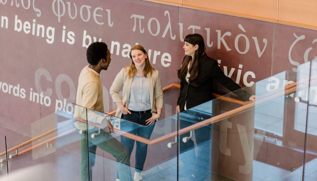 Students and faculty connect in UMBC's public policy building, in front of meaningful quotes in several languages.