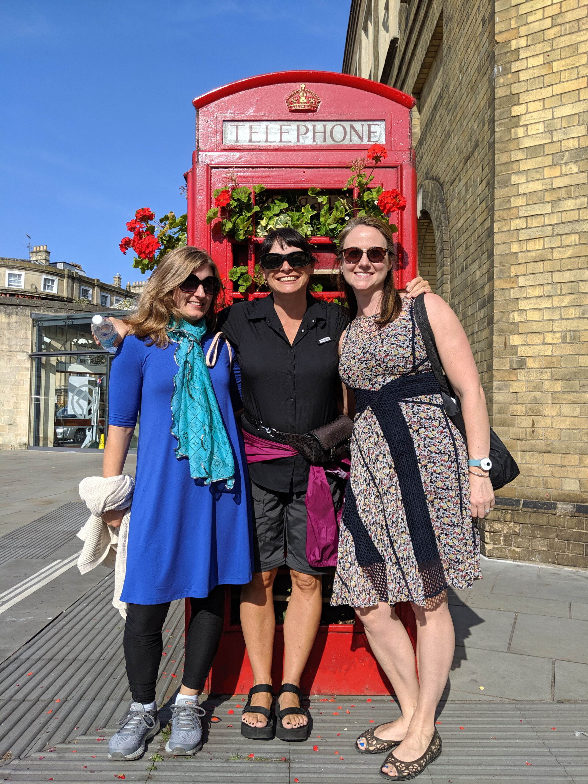 Three women pose in front of telephone booth