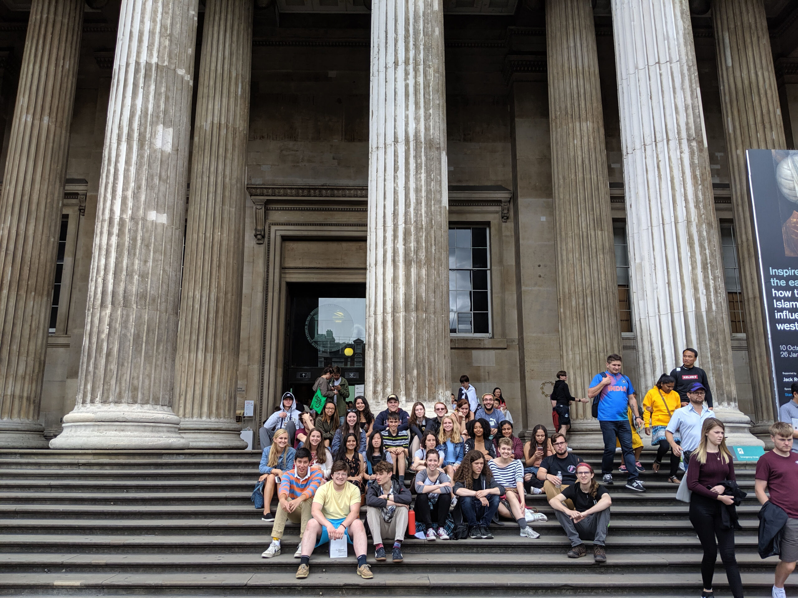 Group of students sit on steps of museum