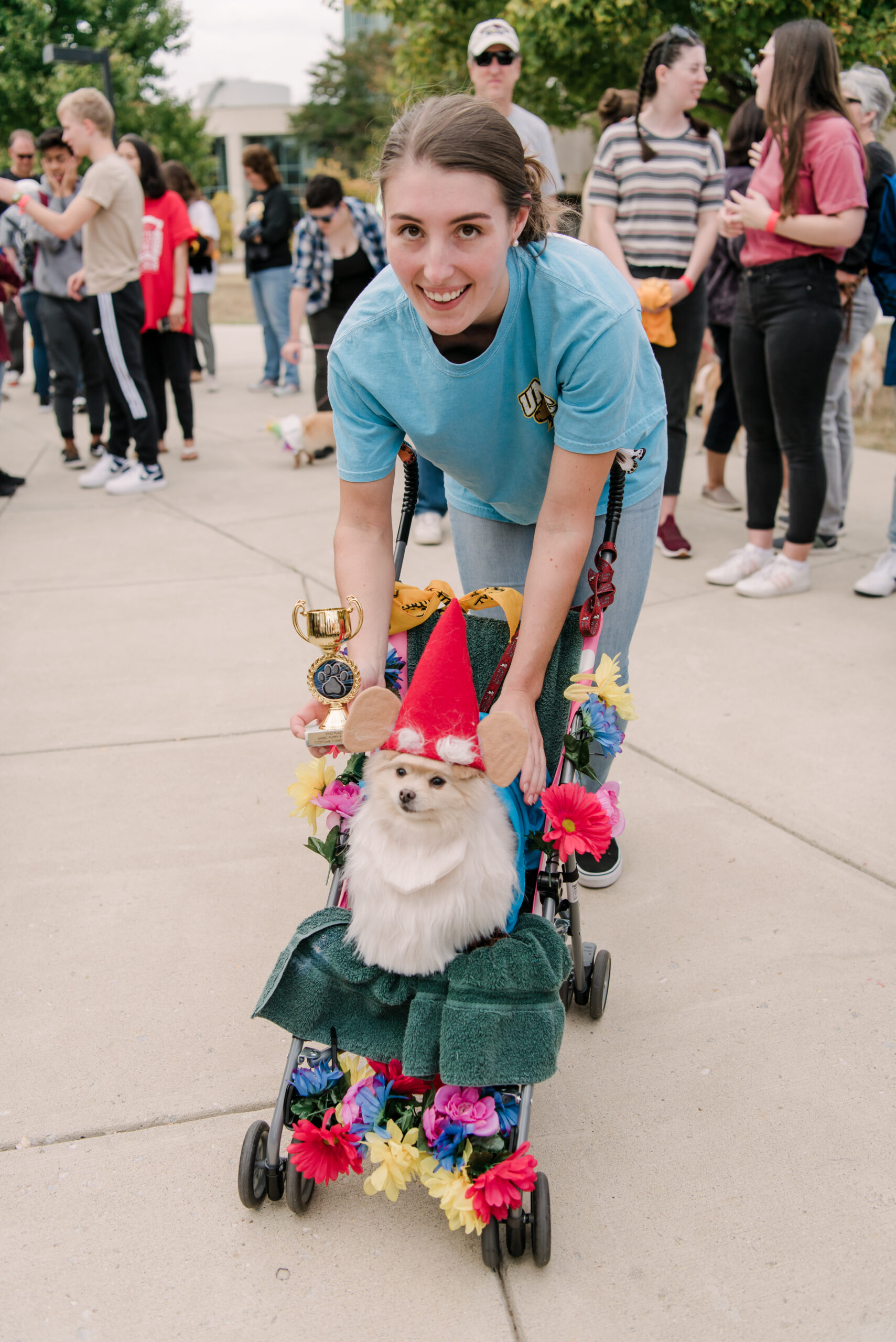 woman holds costumed dog on decorated stroller