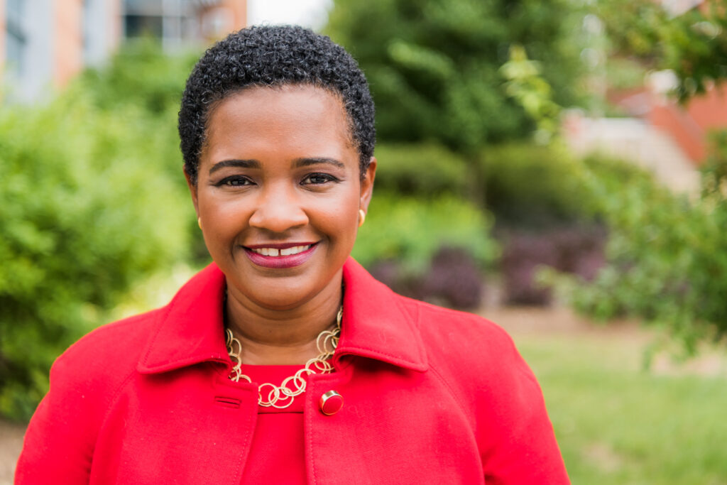 Headshot of a Black woman in bright red suit and jacket.