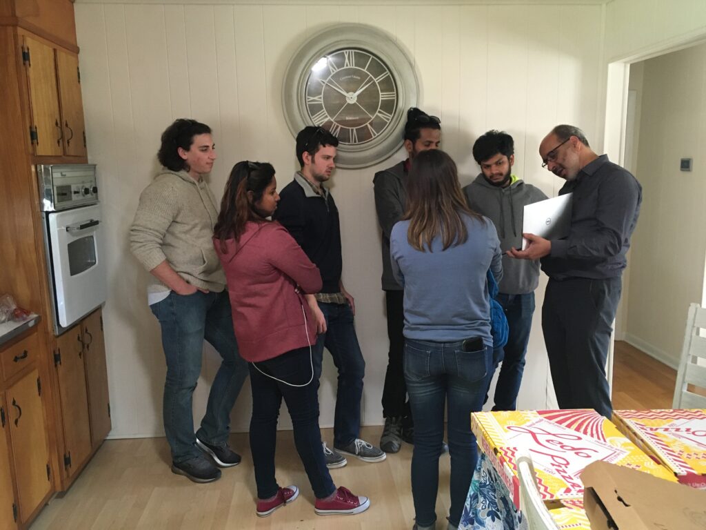 Half a dozen students crowd around Vanderlei Martins, who is pointing to something on his laptop. 