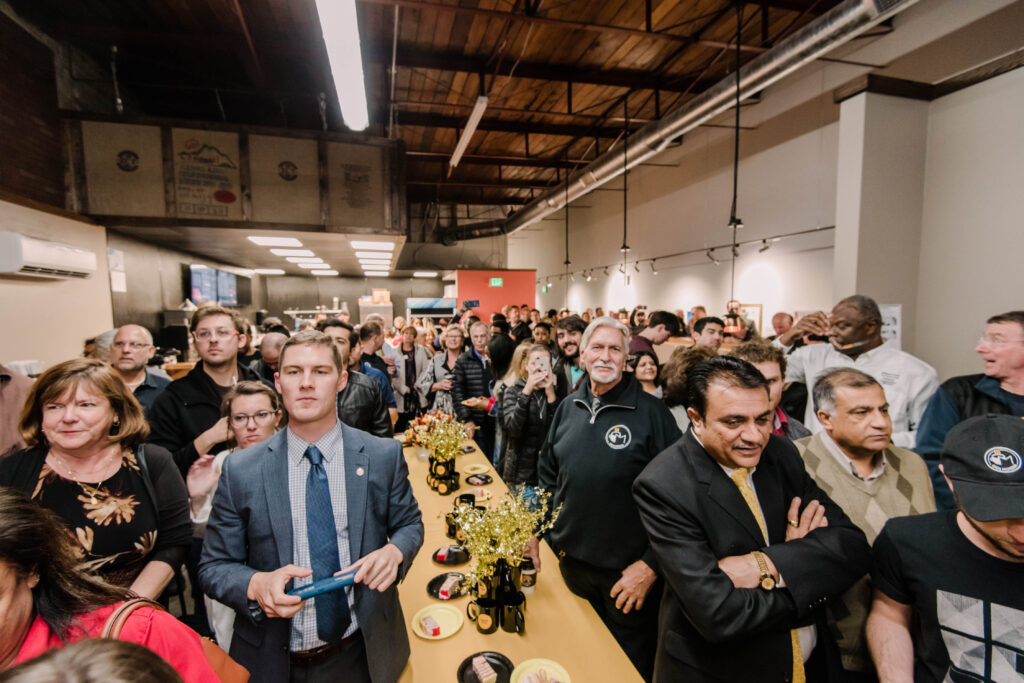 A large crowd of people gathers inside a coffee shop.