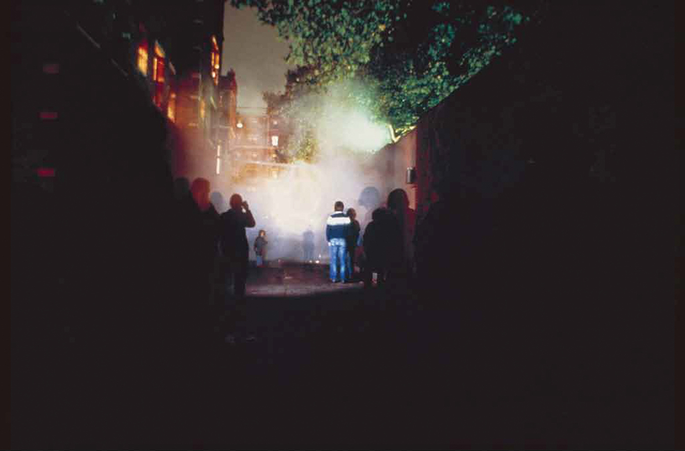 Image of people standing in a smokey alleyway