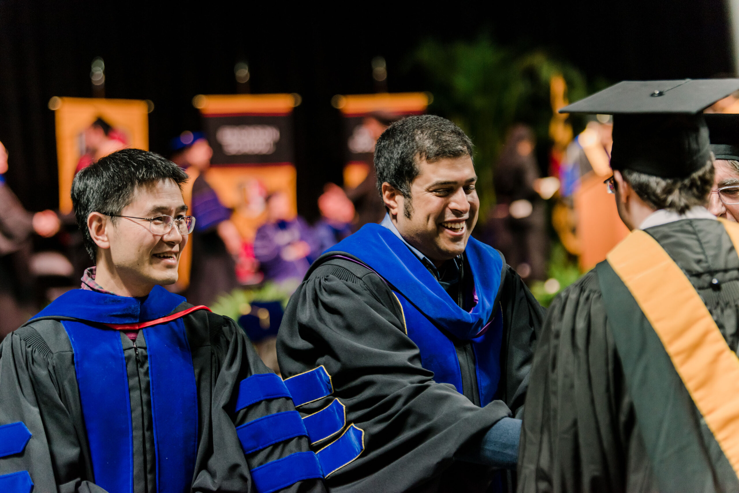 professors in graduation garb interact