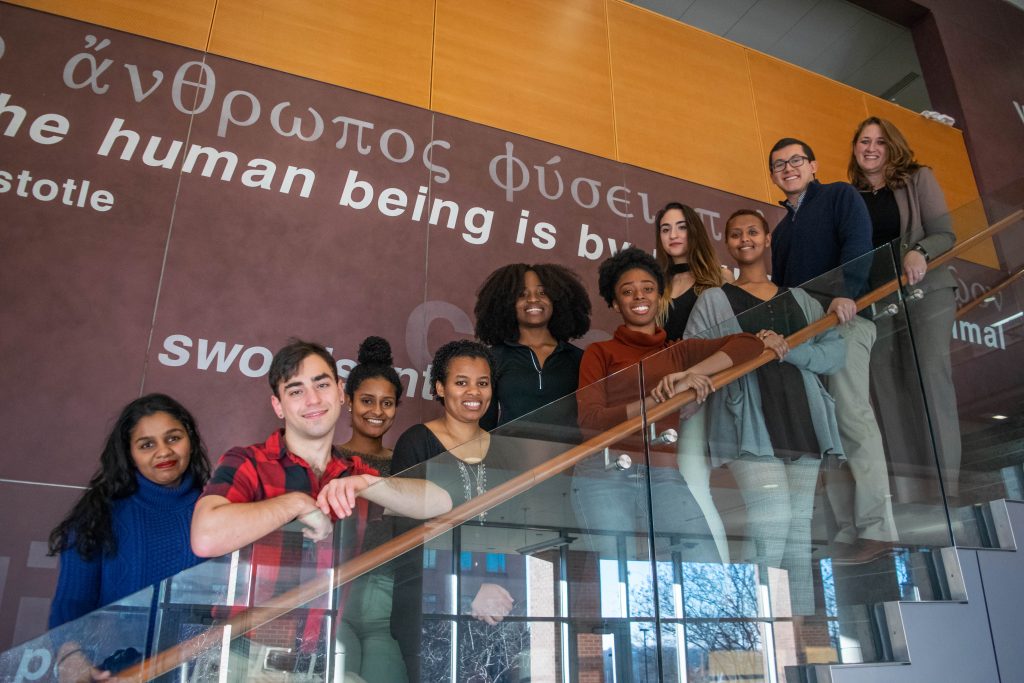 A diverse group of students pose for a photo on a staircase at the Shriver Center.