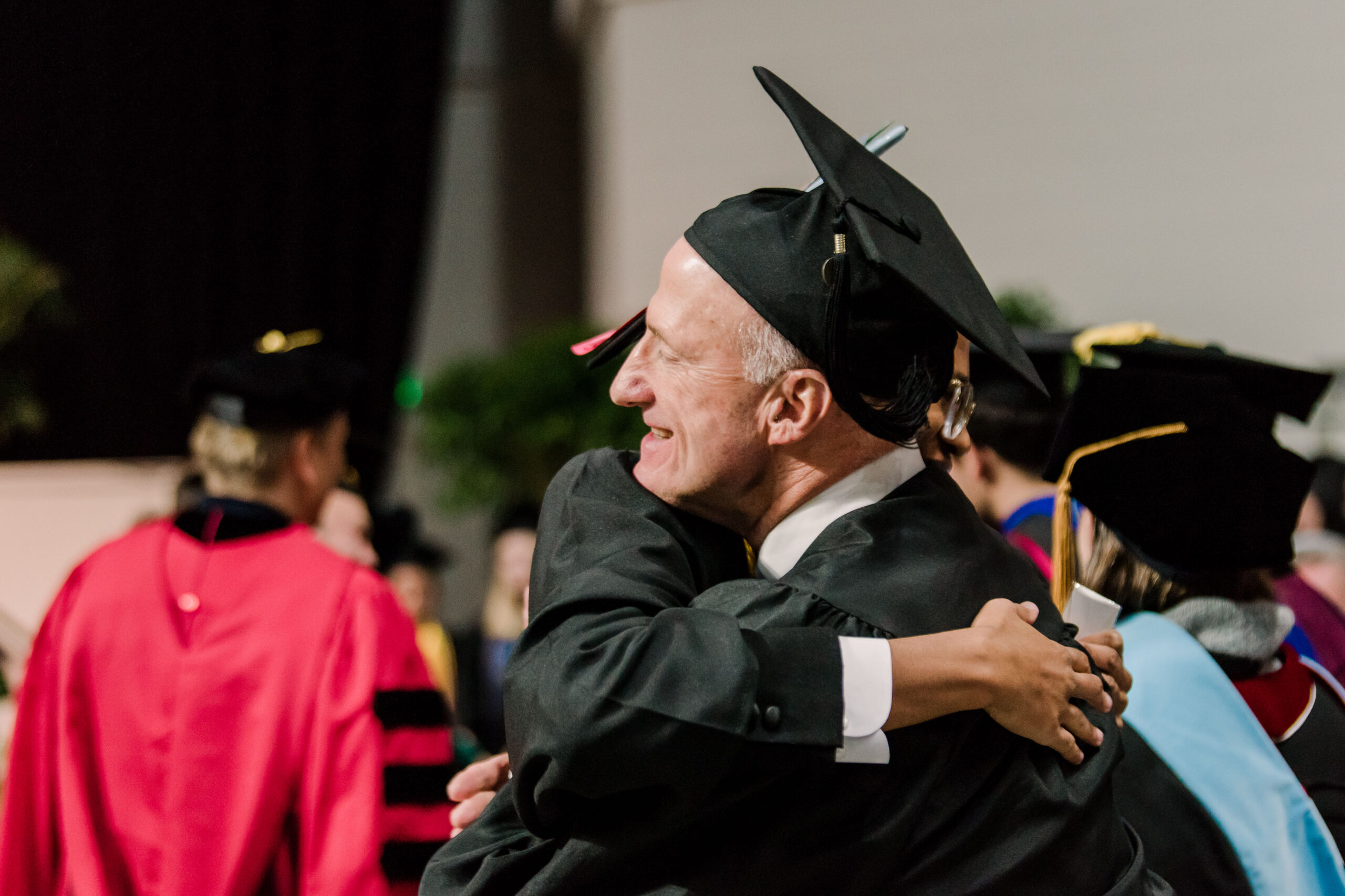 hugging people in graduation garb