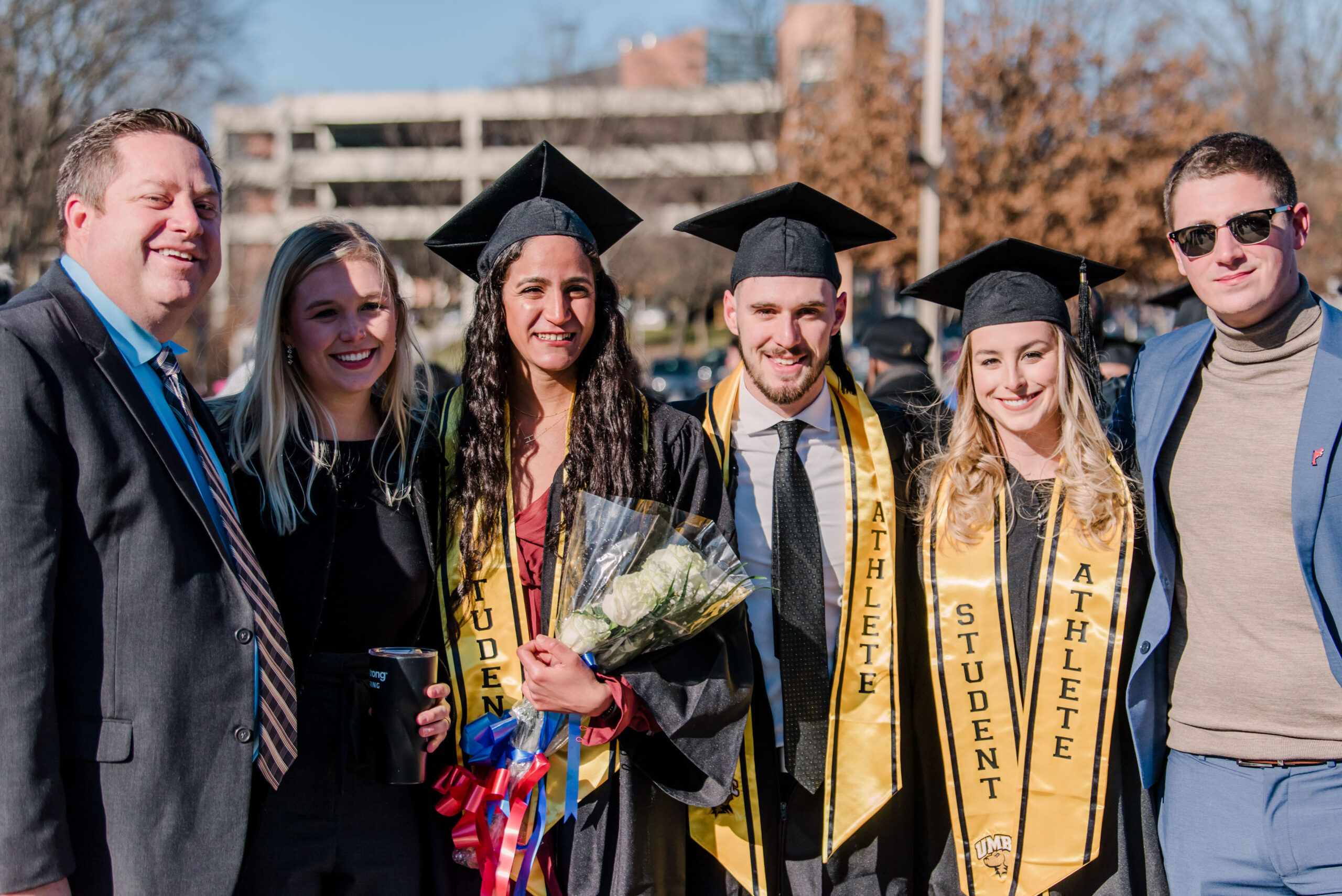 athletic graduate students pose with flowers and others