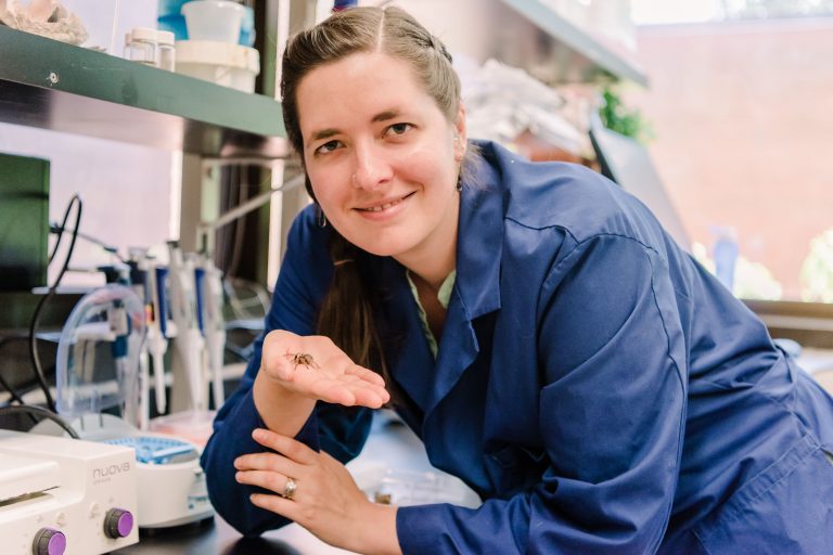 Sarah Stellwagen in a science lab with her pet baby orange-kneed tarantula.