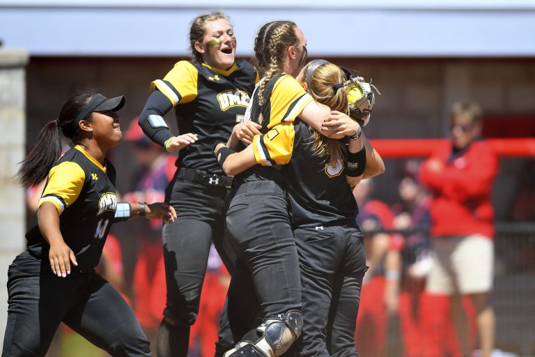 UMBC women's softball players running into a group hug with each other.