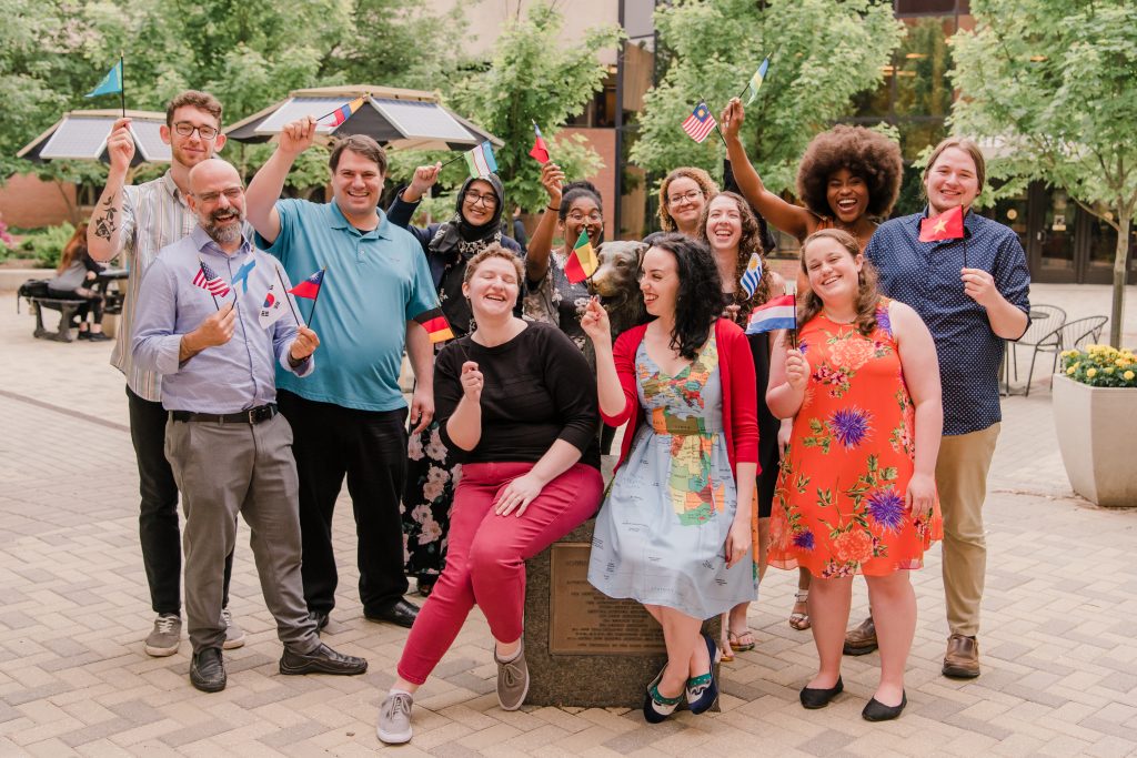 UMBC's Fulbright student recipients stand for a picture waving flags of different countries 