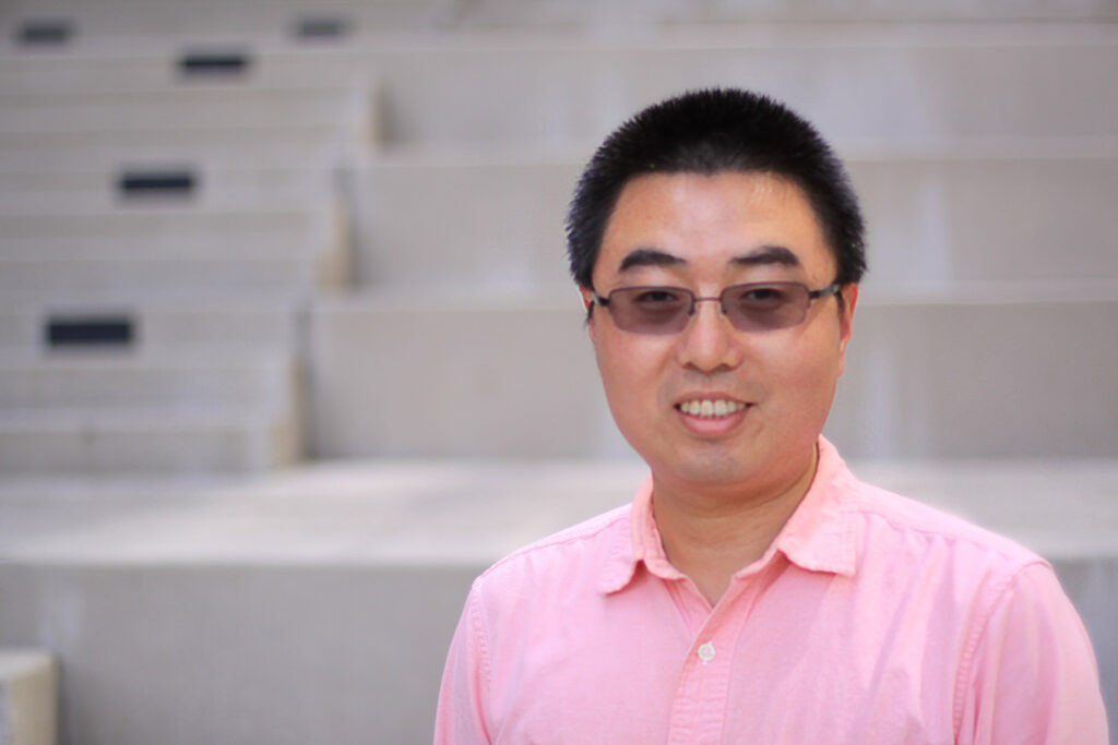 Headshot, Asian man in pink shirt and glasses