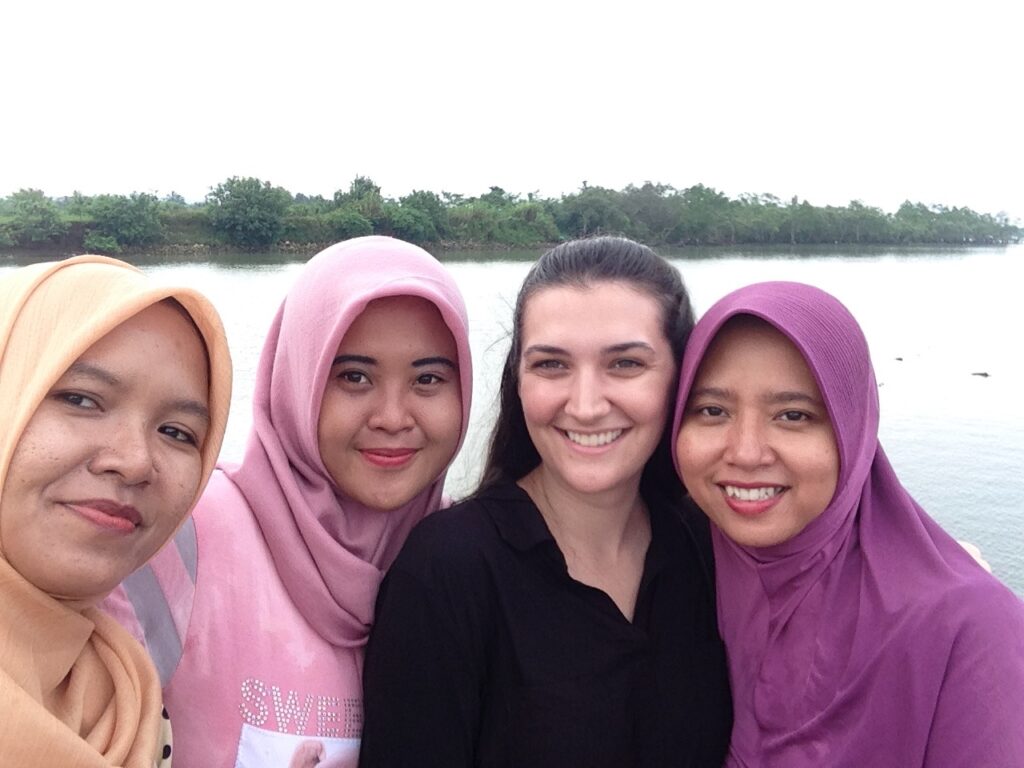 A young woman from the United States wearing a black shirt stands in between three young women from Java, Indonesia who are wearing colorful hijabs.