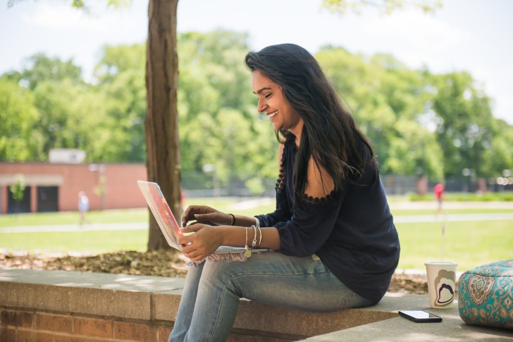 Student outdoors working on a laptop.