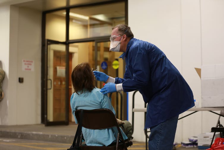 A doctor using a nasal swab to test a state senator of New Mexico.