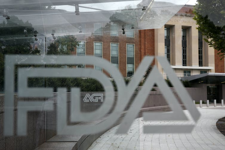 A view of a pane of glass with the FDA logo on it with the FDA building in the background
