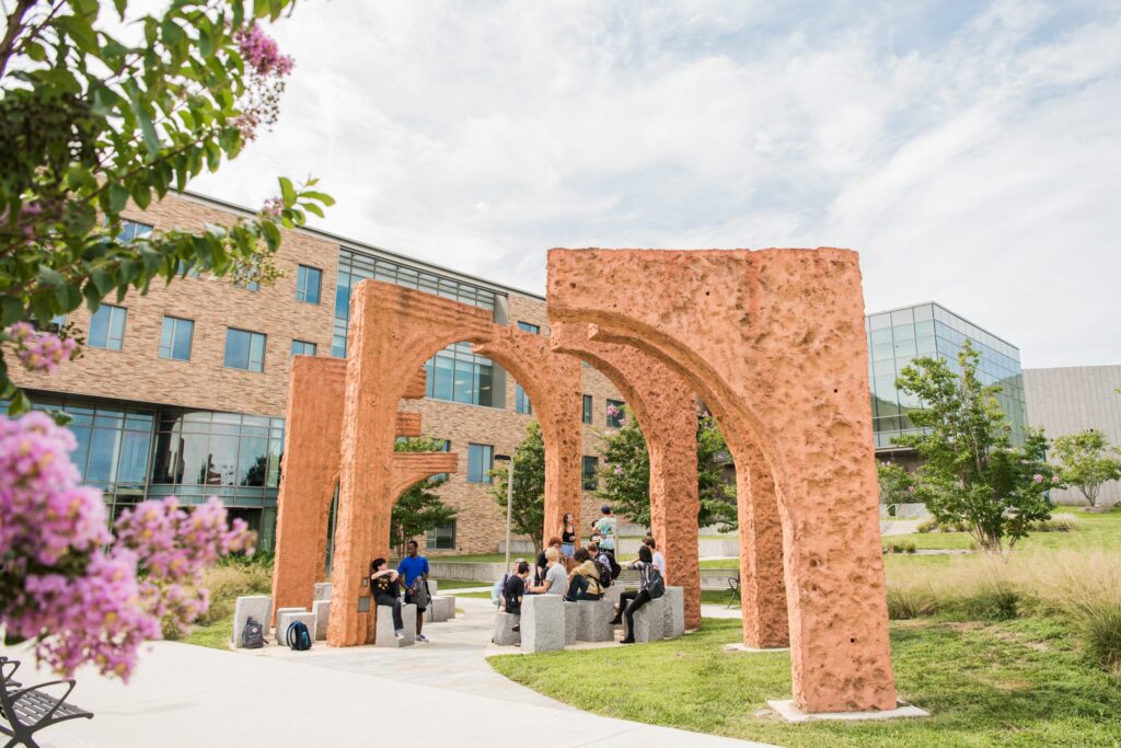 Outdoor archways on UMBC's campus, with students sitting underneath enjoying a nice day outside. 