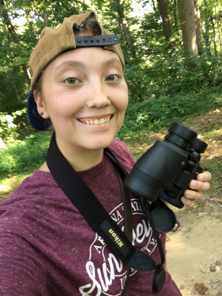 Student outdoors carrying binoculars