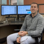 Chris Adams sitting in a chair in front of computer.