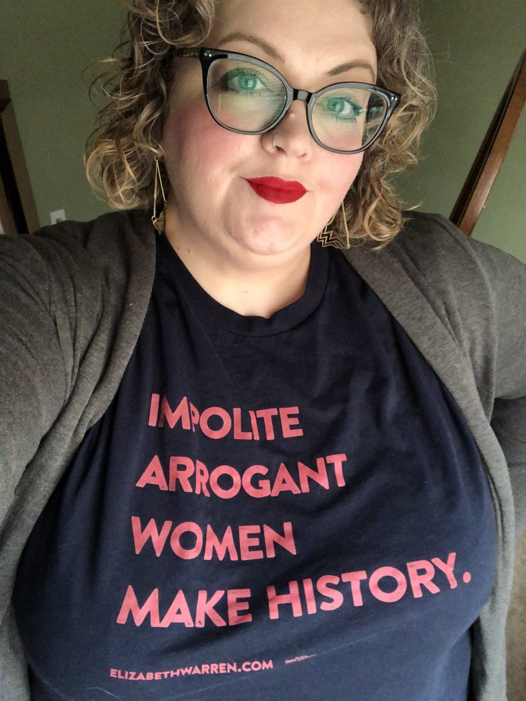 a woman with red lipstick, her shirt reads Impolite Arrogant Women Make History
