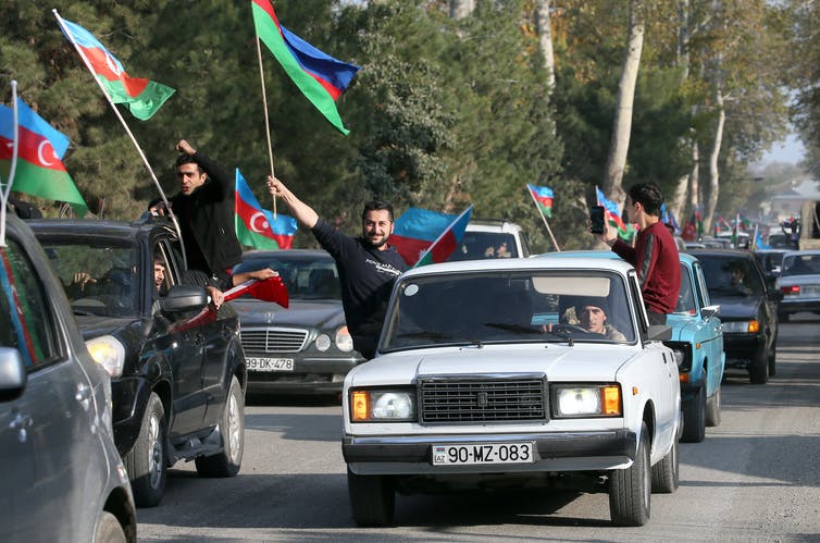 Parade of cars with men waving Azerbaijani flags out the windows