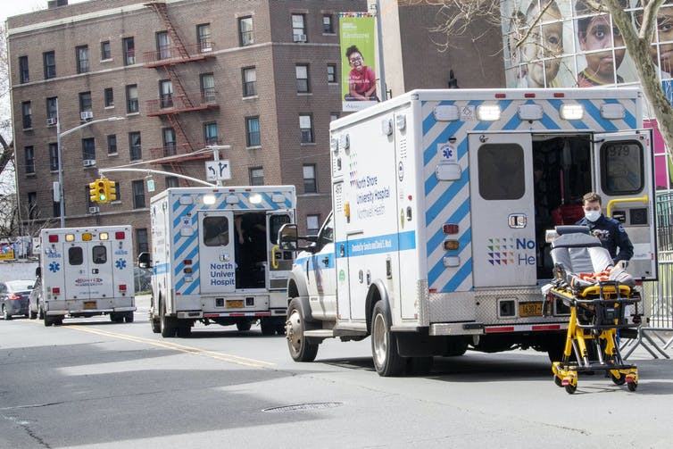 Three ambulances lined up in front of a hospital.