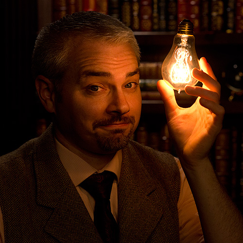 a magician holds a lighted lightbulb