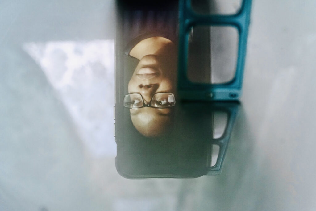 A cellphone reflecting the image of a woman's face upside down