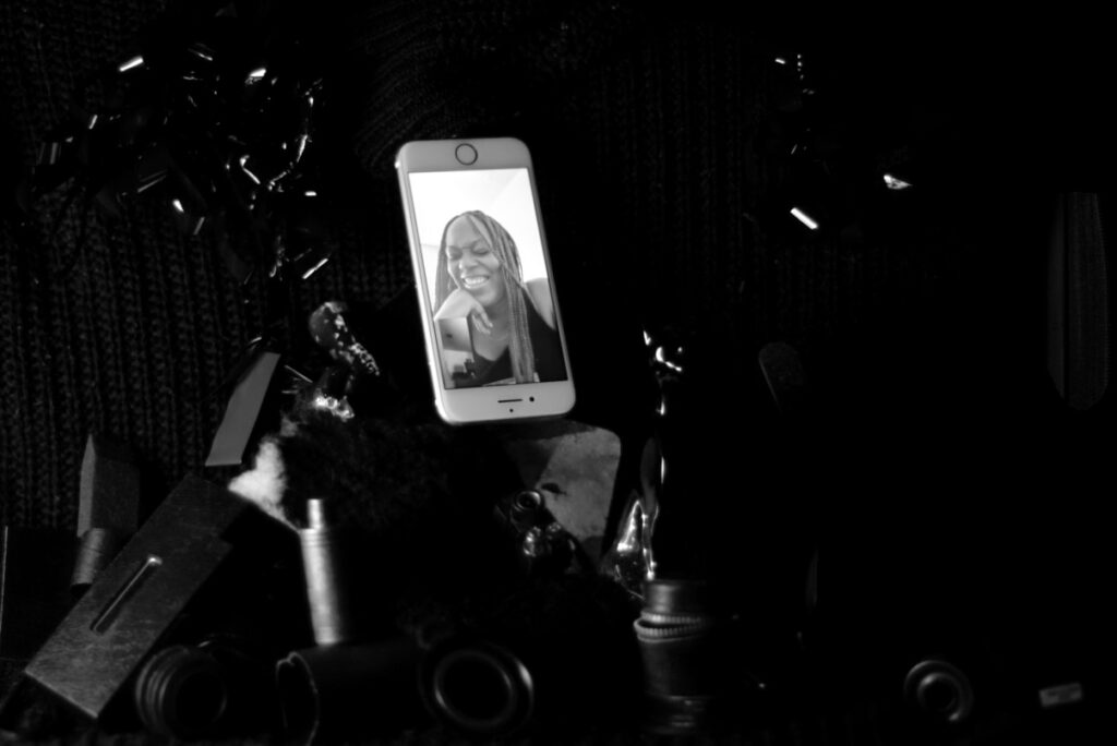 A dark image of an iPhone displaying image of a black woman. The background is very dark and only the light from the iphone is visible.