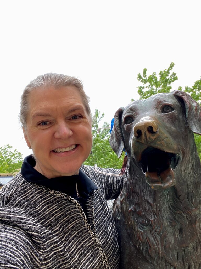 A woman poses with a dog statue.
