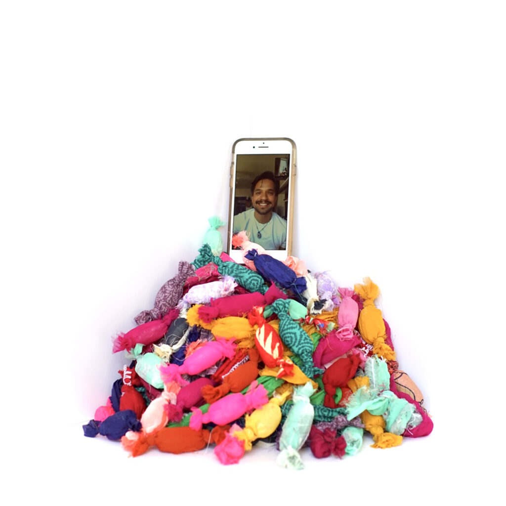 An iPhone displaying a man sits atop pile of colorful beanbags