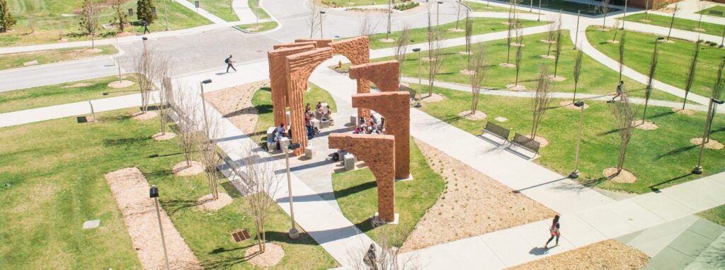 A large outdoor sculpture made of orange colored cement shaped in eight consecutive arches