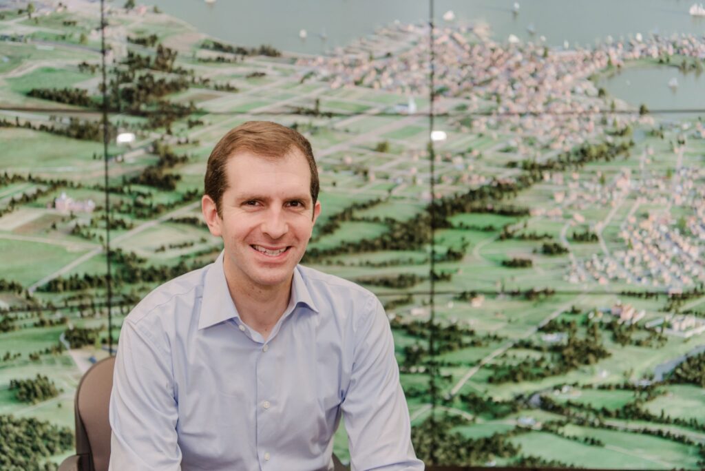 A man smiling in front of a digital map