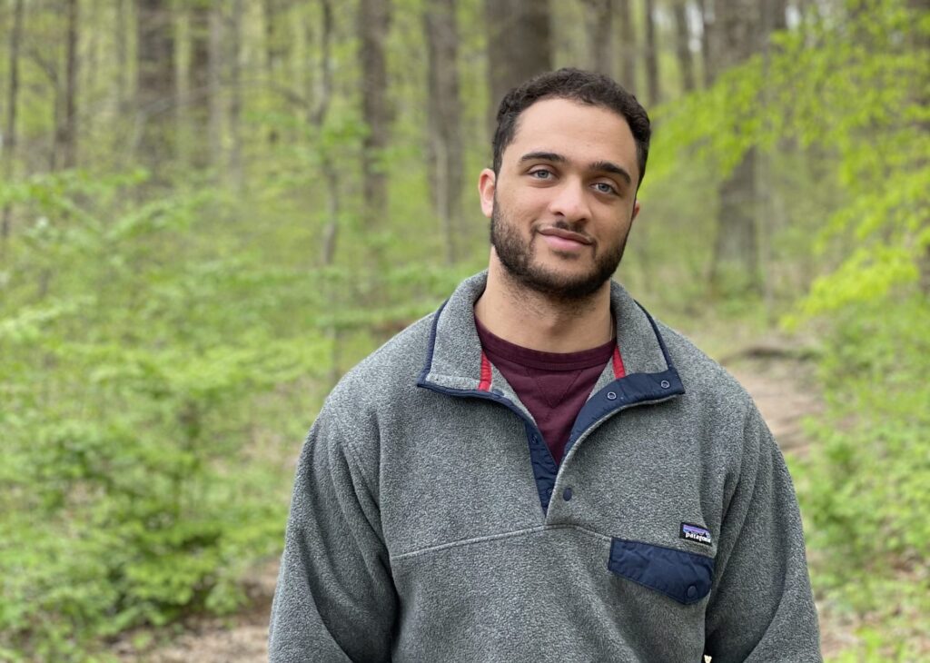 Portrait of a young man in a forest, wearing a gray Patagonia sweater
