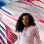 Kizzmekia Corbett stands in front of a colorful art installation in the new Interdisciplinary Life Sciences Building on UMBC's campus.