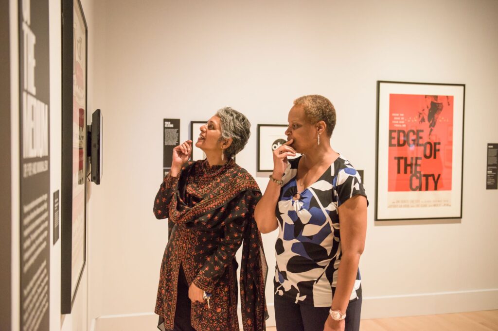 Two women look at artwork in a gallery