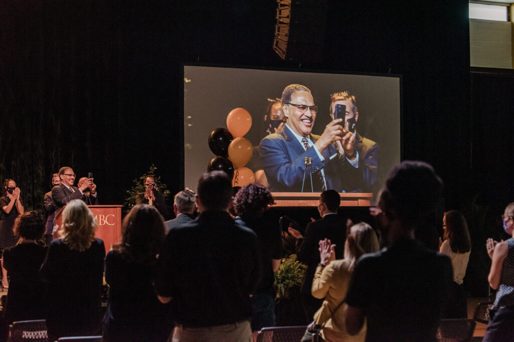 Man at a podium with phone recording audience in front of him