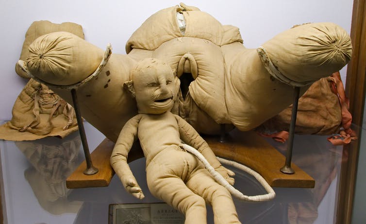 A dummy child attached to a model woman via an umbilical cord.
